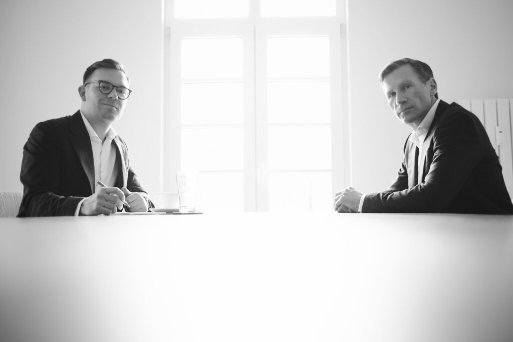 Rechtsanwälte für Familienunternehmen Dr. Armin Weinand, Dr. Philipp S. Weinand sitzen erwartungsvoll an einem Tisch und schauen freundlich in Ihre Richtung und freuen sich über Ihre Kontaktaufnahme und ersten Austausch.
